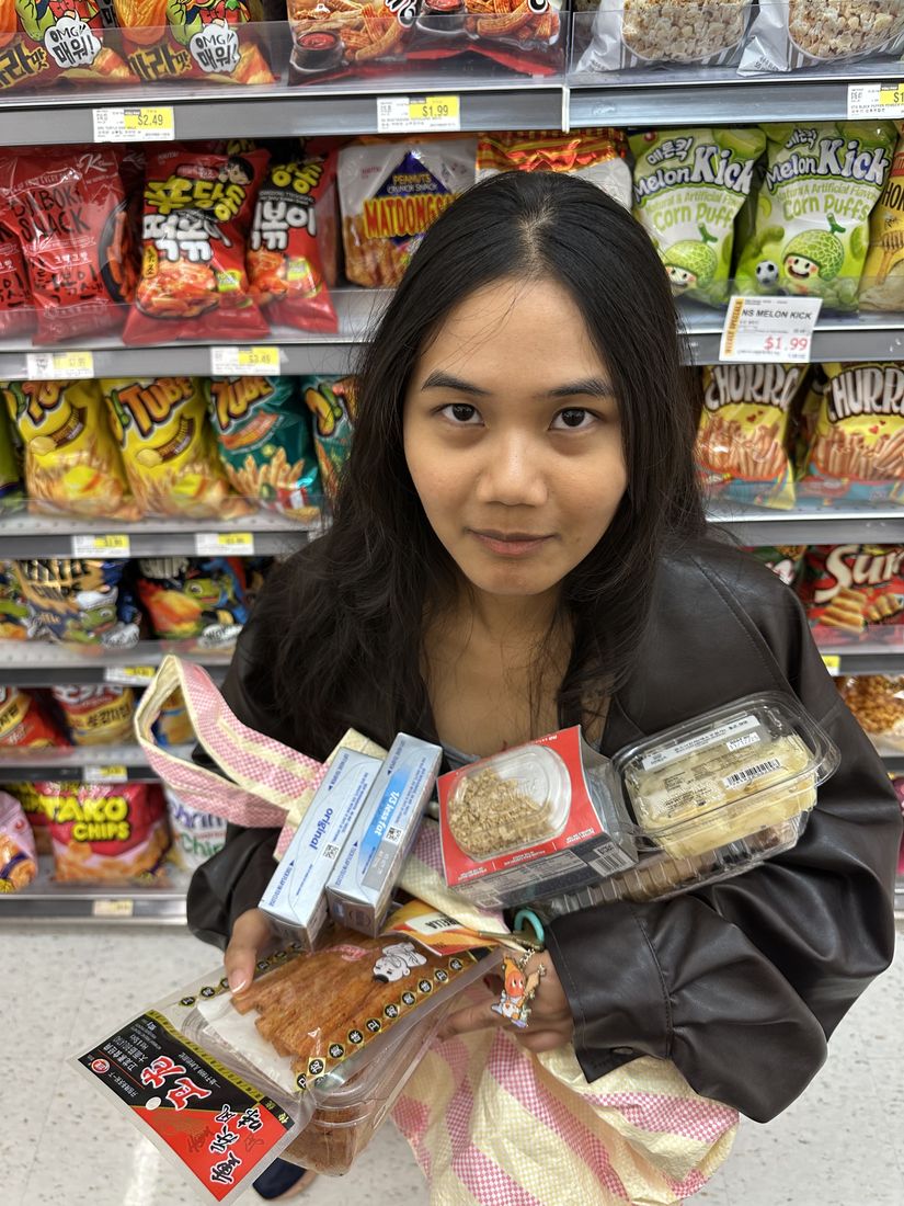 Yas holding an armful of snacks in a shop